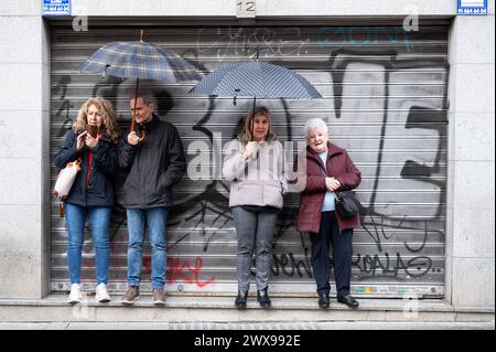 Madrid, Espagne. 29 mars 2024. Les visiteurs se mettent à l'abri de la pluie près de l'église San Pedro el Viejo alors que la procession du jeudi Saint a été suspendue. Madrid a connu des conditions météorologiques défavorables, y compris la pluie et le vent, qui ont forcé l'annulation des processions de Pâques jeudi. Cette décision a été prise pour prévenir les blessures aux pénitents dues aux sols glissants, ainsi que pour sauvegarder l'histoire et le patrimoine inestimables portés par les confréries. (Photo de Miguel Candela/SOPA images/SIPA USA) crédit : SIPA USA/Alamy Live News Banque D'Images