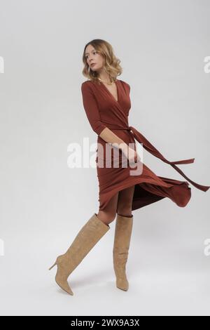 Série de photos de studio de jeune modèle féminin dans une robe portefeuille décontractée en viscose brune Banque D'Images