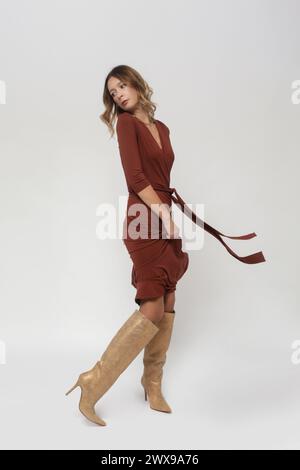 Série de photos de studio de jeune modèle féminin dans une robe portefeuille décontractée en viscose brune Banque D'Images