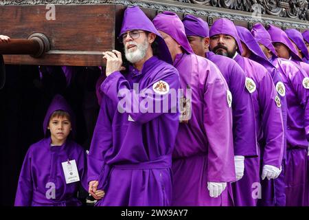 Antigua, Guatemala. 28 mars 2024. Un jeune garçon marche aux côtés de son père, faisant partie des Costaleros transportant le massif flotteur processionnel Jesús Nazareno del Perdón depuis l'église San Francisco El Grande à Semana Santa, le 28 mars 2024 à Antigua, Guatemala. Les processions opulentes, les algèbres détaillées et les traditions séculaires attirent plus d'un million de personnes dans l'ancienne capitale. Crédit : Richard Ellis/Richard Ellis/Alamy Live News Banque D'Images