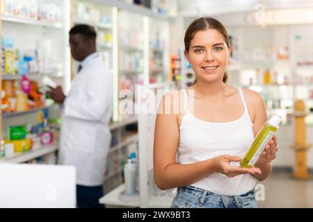 Adolescente choisissant des produits de soins capillaires en pharmacie Banque D'Images