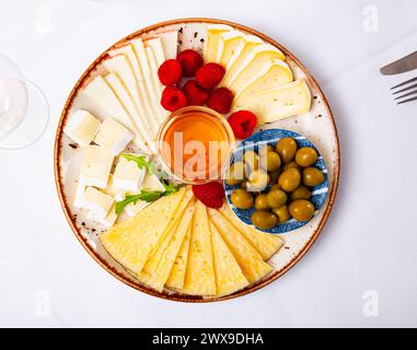 Différents types de fromage, miel, framboises et olives sur bois Banque D'Images