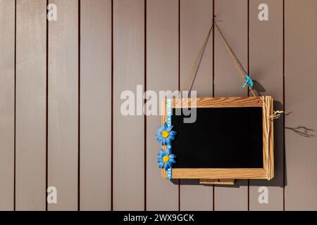 tableau noir avec cadre accroché sur un mur en bois, fleurs de couleur bleue Banque D'Images