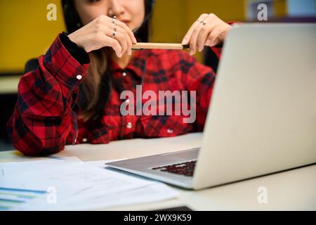 Concentrez-vous sur l'ordinateur portable et les documents sur le bureau pendant le travail de l'opérateur de centre d'appels féminin Banque D'Images