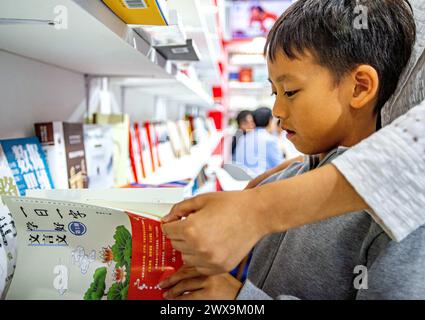 Bangkok, Thaïlande. 28 mars 2024. Un visiteur choisit des livres chinois à la Foire internationale du livre de Bangkok 2024 à Bangkok, Thaïlande, le 28 mars 2024. La foire du livre a débuté ici jeudi et durera jusqu'au 8 avril. Crédit : Wang Teng/Xinhua/Alamy Live News Banque D'Images