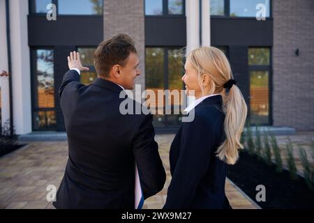 Photo vue arrière de l'agent immobilier montrant la nouvelle maison au client Banque D'Images