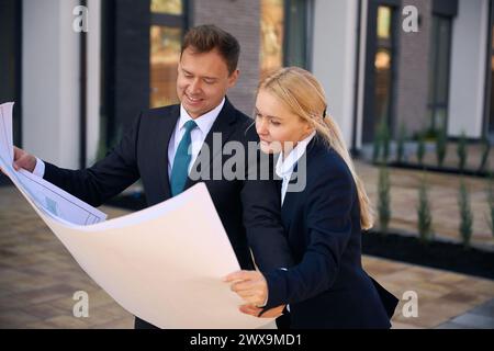 Architecte masculin et cliente féminine regardant le plan de la maison Banque D'Images