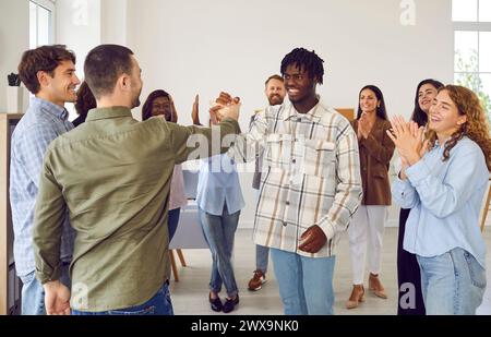 Souriant Groupe diversifié d'amis dans un cercle poignée de main Banque D'Images