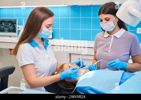 Assistante aide le dentiste à une réception, elle tient l'éjecteur de salive Banque D'Images