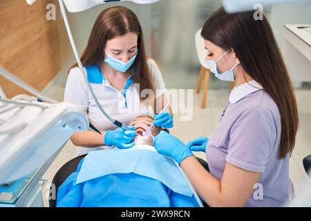 Jeune femme dentiste avec assistant traite les dents de l'adolescente Banque D'Images