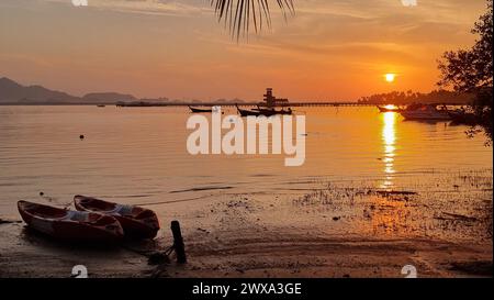 Un bateau coloré repose paisiblement sur la plage de sable, surplombant le vaste océan. Koh Mook Thaïlande Banque D'Images