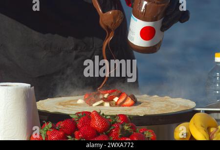 Le corps de la section médiane d'un chef préparant des crêpes de fruits sucrés, des crêpes françaises au marché fermier Stall à Prague Naplavka, République tchèque Banque D'Images