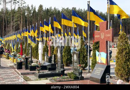 Irpin, UKRAINE - 28 MARS 2024 - des drapeaux nationaux flottent sur les tombes des défenseurs périmés de l'Ukraine au cimetière de la ville d'Irpin à l'occasion du deuxième anniversaire de la libération de la ville des envahisseurs russes, Irpin, région de Kiev, dans le nord de l'Ukraine. Banque D'Images