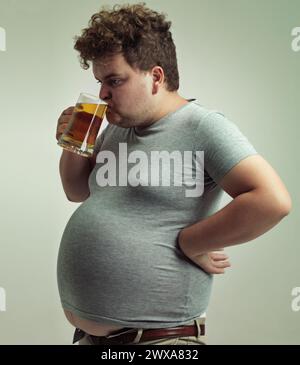 Plus la taille, l'homme et boire de l'alcool pour l'habitude malsaine, le ventre et le gain de poids dans le studio de fond blanc isolé. Estomac, bière et personne masculine Banque D'Images