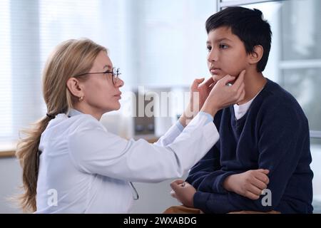 Vue de côté portrait d'une pédiatre examinant un jeune garçon pendant le bilan de santé en clinique Banque D'Images