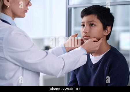 Portrait d'un jeune garçon moyen-oriental hospitalisé avec un médecin examinant le cou et la gorge pendant le bilan Banque D'Images