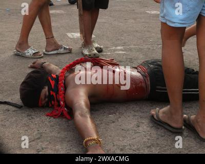 Navotas, Philippines. 29 mars 2024. (NOTE DE LA RÉDACTION : L'image contient du contenu graphique)Un flagellant se trouve sur le sol en attendant d'être pagayé. Dans leur façon de demander la repentance et le pardon pour leurs péchés, les flagellants fouettent leur dos en utilisant des bandes de bambou et se font pagayer jusqu'aux fesses le vendredi Saint. Crédit : SOPA images Limited/Alamy Live News Banque D'Images