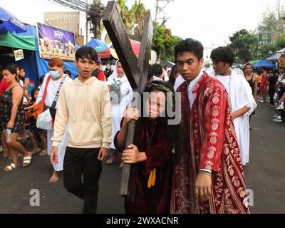 Navotas, Philippines. 29 mars 2024. Une femme habillée en Jésus Christ, portant une croix comme un acte de pénitence. Dans leur façon de demander la repentance et le pardon pour leurs péchés, les flagellants fouettent leur dos en utilisant des bandes de bambou et se font pagayer jusqu'aux fesses le vendredi Saint. Crédit : SOPA images Limited/Alamy Live News Banque D'Images