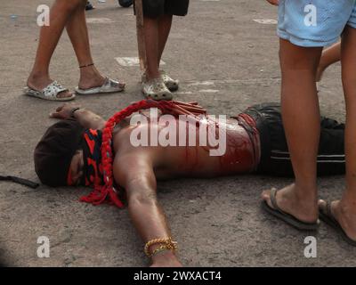 Navotas, Philippines. 29 mars 2024. (NOTE DE LA RÉDACTION : L'image contient du contenu graphique)Un flagellant se trouve sur le sol en attendant d'être pagayé. Dans leur façon de demander la repentance et le pardon pour leurs péchés, les flagellants fouettent leur dos en utilisant des bandes de bambou et se font pagayer jusqu'aux fesses le vendredi Saint. (Photo Josefiel Rivera/SOPA images/SIPA USA) crédit : SIPA USA/Alamy Live News Banque D'Images