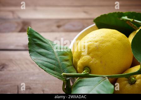 Gros plan de quelques citrons dans un bol en céramique sur un comptoir de cuisine en bois Banque D'Images