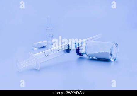 Vaccin en flacon et seringue gros plan sur fond bleu, concept médical, laboratoire, vaccination par injection sous-cutanée, dose. Immunisation dans le tr Banque D'Images