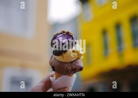 Main tenant un cône de crème glacée chocolat et vanille avec fond de rue flou Banque D'Images