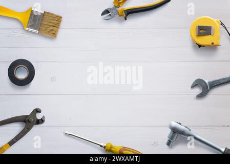 Vue de dessus des outils assortis soigneusement disposés sur un bureau en bois blanc, avec un espace de copie au centre. Composition de pose à plat idéale pour la promotion du concept de bricolage Banque D'Images