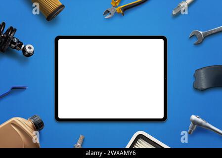 Maquette de tablette avec écran isolé pour la promotion d'application ou de page Web entourée de pièces de voiture et d'outils. Concept de service de voiture ou de vente de pièces Banque D'Images