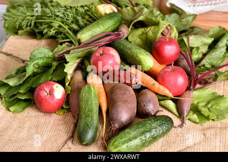 Sur la photo, les légumes mûrs, les betteraves, les concombres, les carottes et les pommes reposent sur la table. Banque D'Images