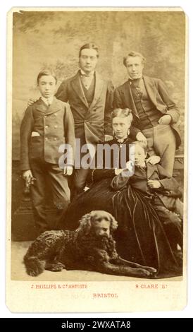 Carte de visite victorienne originale des années 1860 (carte de visite ou CDV) d'une famille victorienne, enfants avec leur mère, père et oncle, le chien de la famille est assis à leurs pieds. La mère est une jolie dame portant une robe de velours, du studio de J. Phillips & Co. Artistes, 9 Clare préparées Bristol, vers 1865. Banque D'Images