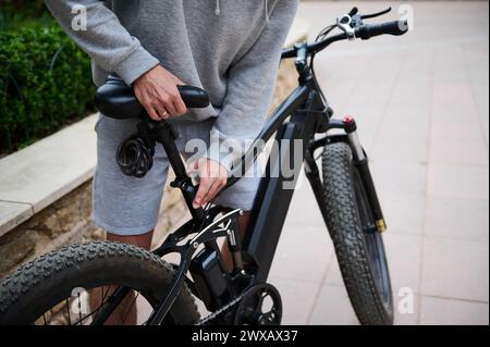 Vue rognée. Homme cycliste ajustant un siège sur un vélo alimenté par batterie avant de rouler. Louer un vélo électrique comme transport urbain écologique. Les gens. AC Banque D'Images