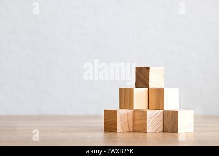 Blocs de bois disposés en forme de pyramide sur une surface en bois avec un fond Uni. Banque D'Images