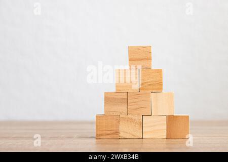 Une pyramide soigneusement empilée de blocs de bois sur un fond Uni. Banque D'Images