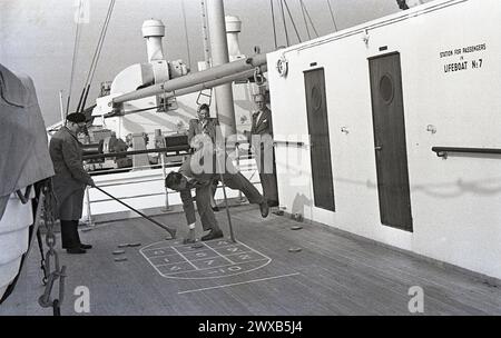 Années 1950, historique, passagers masculins sur le pont jouant des quiots, avis sur le mur, Station for Passengers in Lifeboat No 7 Banque D'Images