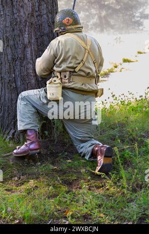 Reconstruction historique. Un soldat d'infanterie américain de la seconde Guerre mondiale combattant dans la forêt. Vue de l'arrière. Banque D'Images