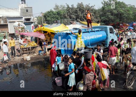 Les gens se rassemblent autour d'un camion-citerne pour s'approvisionner dans un environnement urbain, Rajasthan, Inde du Nord, Inde Banque D'Images