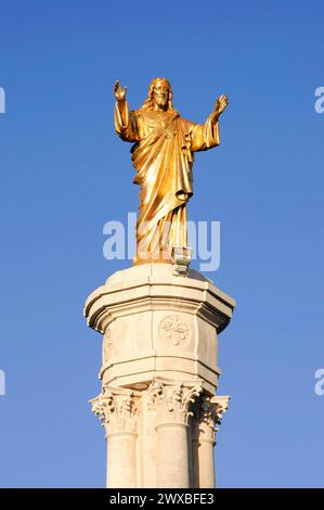 Statue du Christ, Fatima, lieu de pèlerinage, centre du Portugal, statue dorée de Jésus aux bras tendus devant un ciel bleu, nord du Portugal Banque D'Images