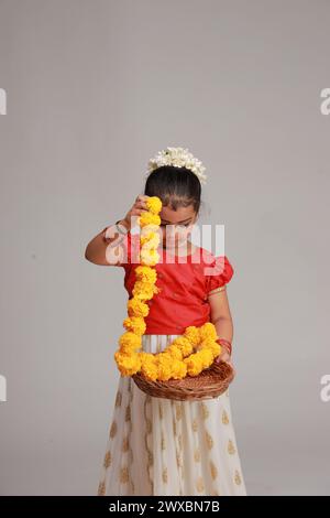 Un enfant mignon petite fille portant robe Kerala-robe-couleur dorée jupe longue et chemisier rouge, thème du festival onam, fond blanc isolé. Banque D'Images