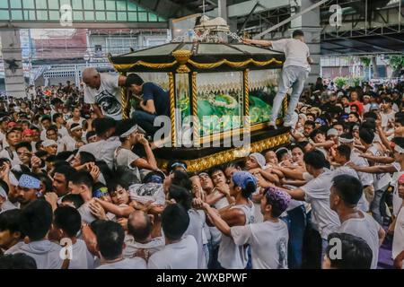 29 mars 2024, Binangonan, Rizal, Philippines : les dévots catholiques luttent pour manœuvrer le transport de Jésus mort à Binangonan, Rizal le vendredi Saint, 29 mars 2024. Le gewang-gewang, un mot tagalog qui se traduit par ''balancement'' en anglais, est une tradition du vendredi Saint où la plupart des hommes sont les participants. Cette vénérable tradition se concentre sur le transport du Santo Entierro ou l'icône morte de Jésus de sa maison particulière à une église tandis qu'à l'intérieur du chariot de cercueil en verre transporté principalement par des hommes dévoués pendant la procession qui est semblable au Traslacion du Nazaréen noir de Banque D'Images