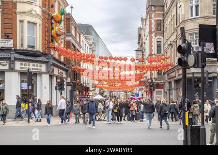 L'agitation des gens dans Wardour Street à l'entrée de Chinatown, Londres. Surveillé et accueilli par la sculpture emblématique du lion chinois. Banque D'Images