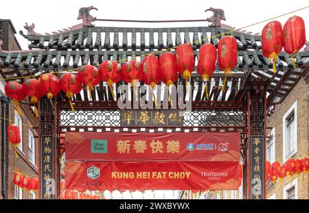 Une porte chinoise colorée, des lanternes rouges et des bannières dans Gerrard Street, Chinatown, Londres. Salutation traditionnelle du nouvel an Kung Hei Fat Choy . Banque D'Images