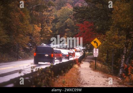 Voitures en Nouvelle-Angleterre suivant la Kancamagus Highway dans le New Hampshire pour voir le feuillage d'automne par un jour humide d'octobre. Banque D'Images