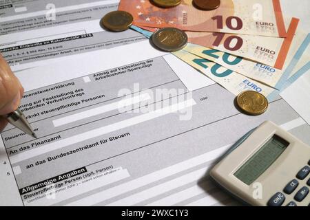 Un stylo à bille tenu par les doigts d'un homme remplissant un formulaire fiscal allemand. Banque D'Images