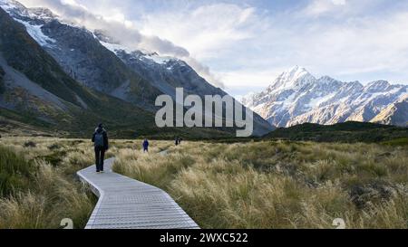 Touristes marchant sur la promenade en bois menant à travers la belle vallée alpine, Mt Cook, Nouvelle-Zélande. Banque D'Images