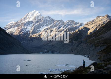 Femme debout dans un beau paysage avec glacier, lac glacier et énorme montagne enneigée, Nouvelle-Zélande. Banque D'Images