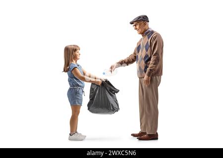 Plan de profil pleine longueur d'un homme senior jetant une bouteille en plastique et une petite fille tenant un sac à déchets isolé sur fond blanc Banque D'Images