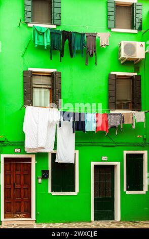 linge suspendu à des cordes à linge suspendues entre les fenêtres sur un mur vert Banque D'Images