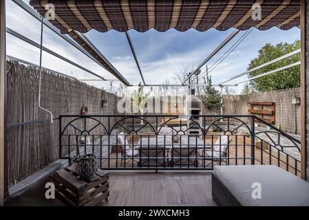 une terrasse remplie de plantes avec des meubles en métal lisse et des séparateurs en osier pour l'intimité avec des escaliers avec des balustrades en métal peint en noir Banque D'Images