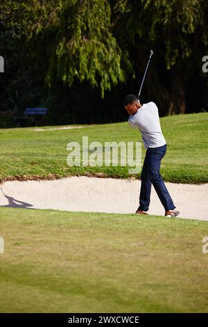 Homme, golfeur et swing avec club sur la fosse de sable pour par, bogey ou coup avec terrain d'herbe dans la nature. Personne masculine ou joueur de sport frappant la balle dehors pour Banque D'Images