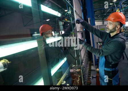 L'homme dans un casque de sécurité travaille dans un atelier de production Banque D'Images